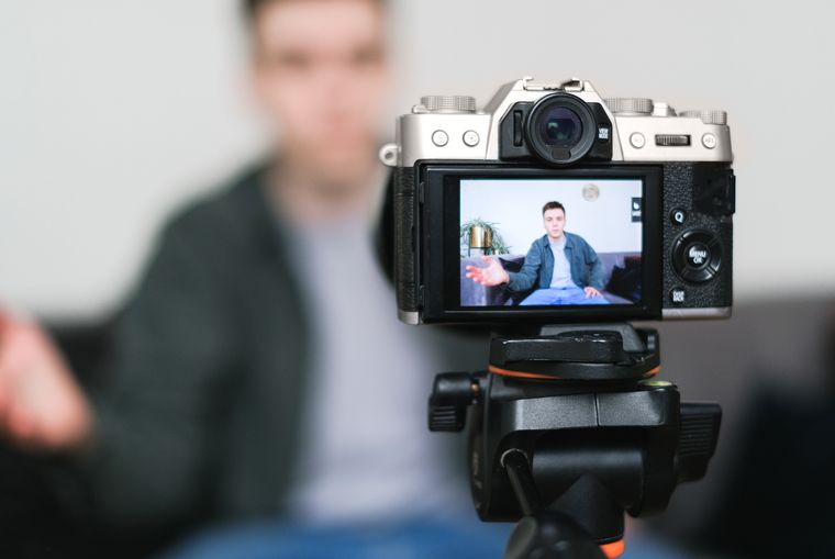 YouTube kanalı için tripod üzerinde kamerayla video çeken içerik üretici