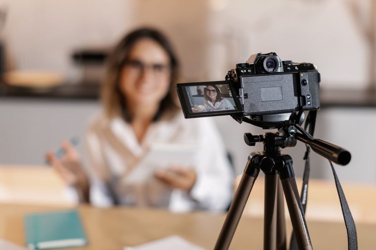 Kamera ve tripodla YouTube videosu çeken kadın içerik üretici
